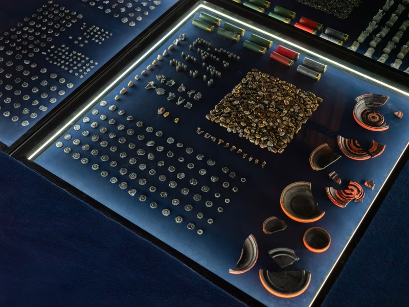 Rounded objects and small fragments arranged inside an illuminated module, beside curved pieces in earth tones.
