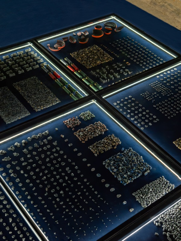 A vertical detail of two modules with small objects in rows and circular fragments against a blue background.
